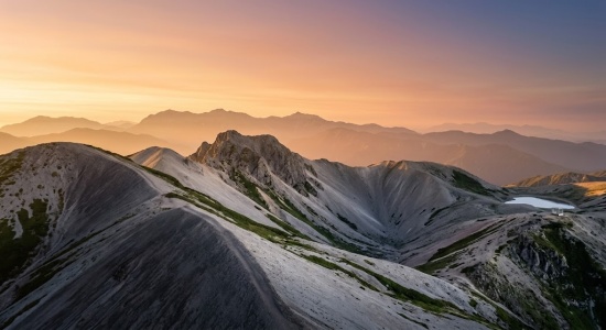 「夕日に染まる険しい山々と稜線が連なる山岳風景を捉えた絶景」